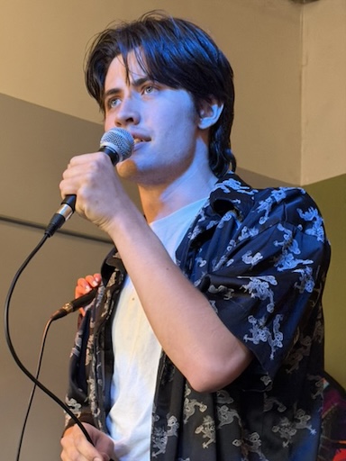 Jake holding a microphone, a blue light hits his face