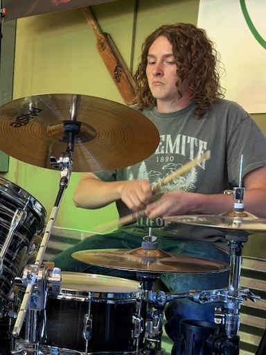 Wyatt sitting at the drumset, playing them